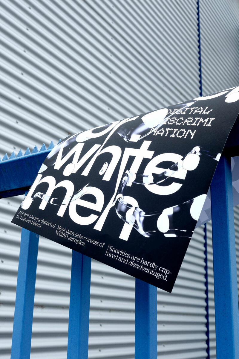 blauer Zaun vor grauer Garage, darüber liegt ein Plakat